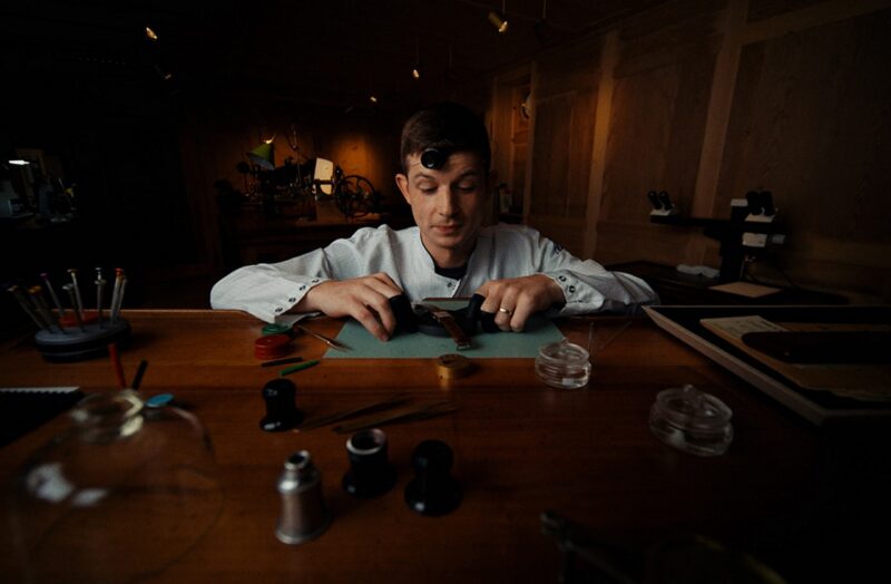 Watchmaker with a loupe working at a wooden restoration bench