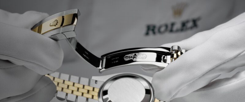 Gloved hands inspecting the back of a Rolex watch