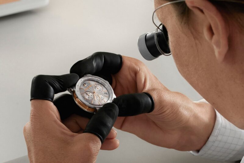 Watchmaker inspecting an Audemars Piguet watch through a loupe