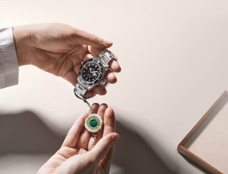 Hands presenting a Rolex watch and Certified Pre-Owned seal