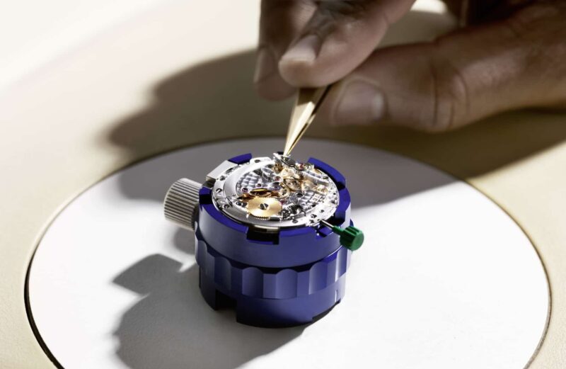 A watchmaker working on a Rolex movement in a blue movement holder
