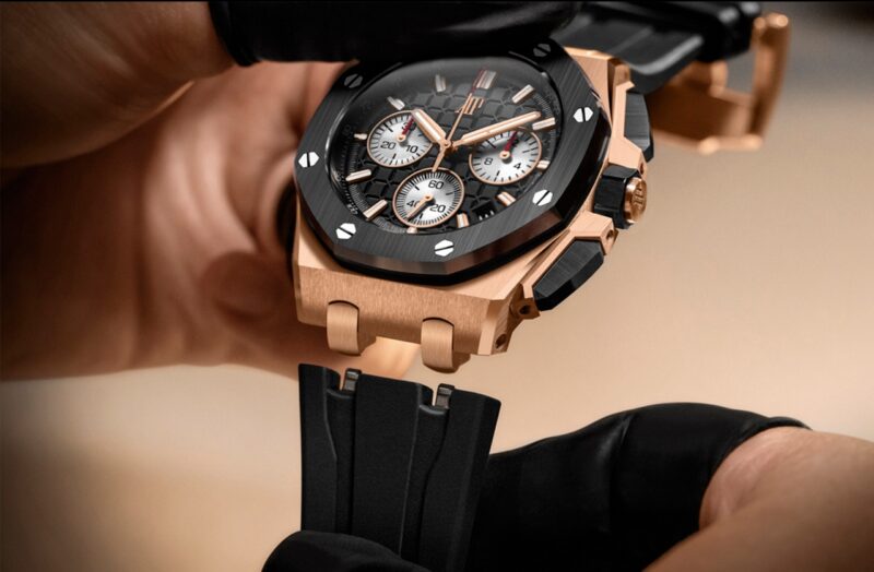 Hands holding an Audemars Piguet chronograph with a dark strap