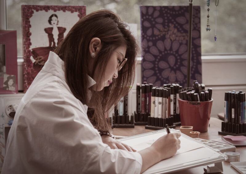 Chopard designer drawing at a desk beside pencils and designs