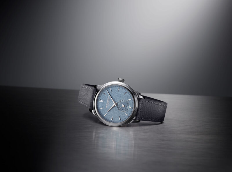 Blue-grey dial Chopard wristwatch with a dark strap on a reflective surface