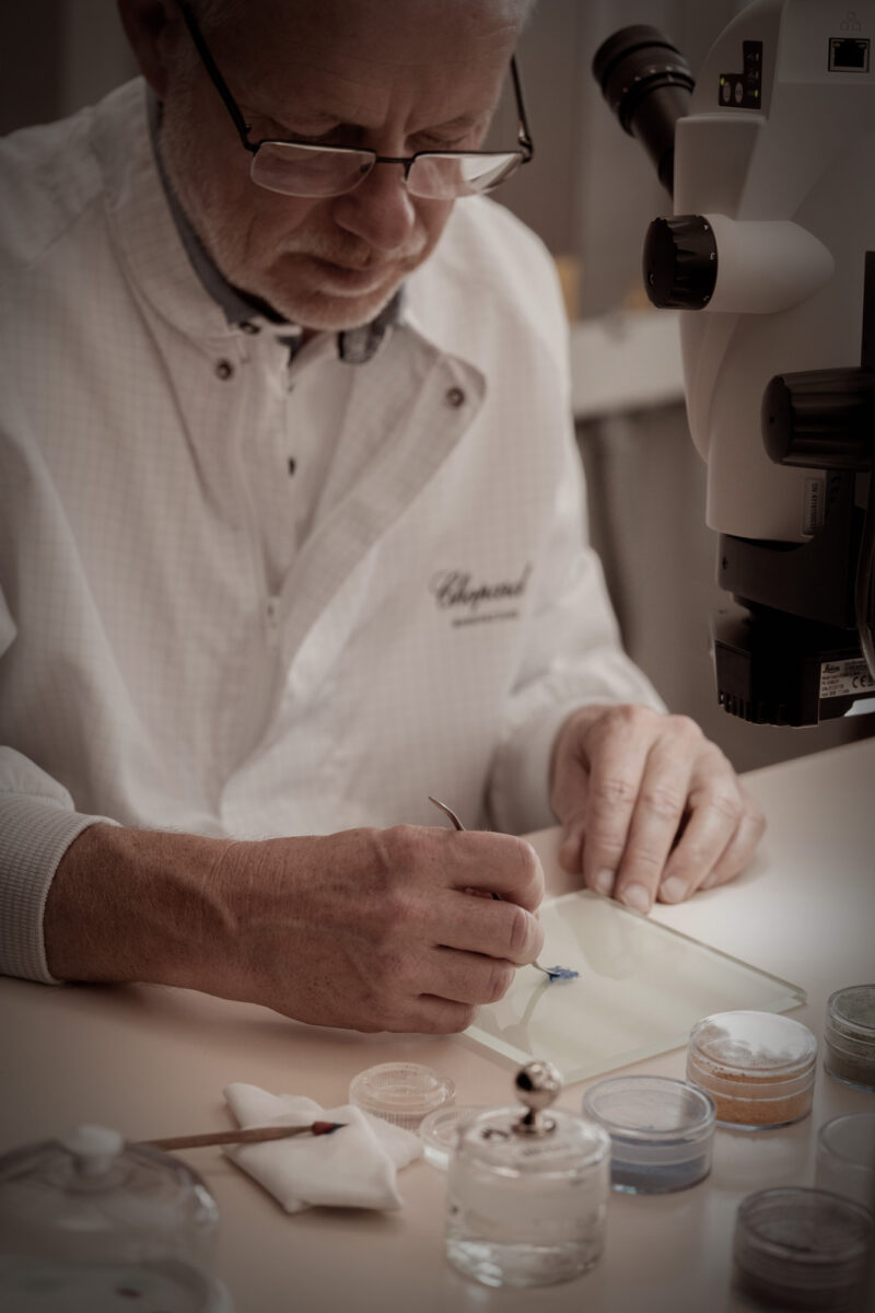 Chopard artisan wearing glasses and a white coat working at a jeweller’s bench