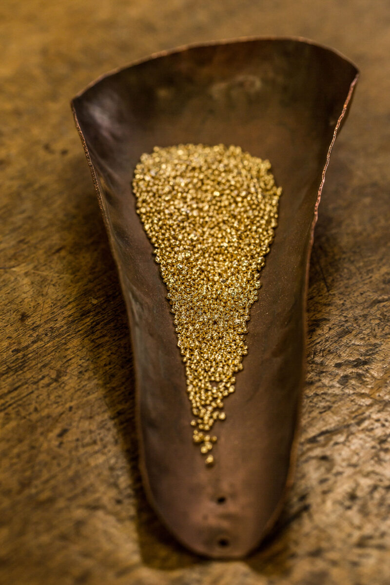 Small gold-coloured grains in a worn shallow container in official Chopard sourcing photography