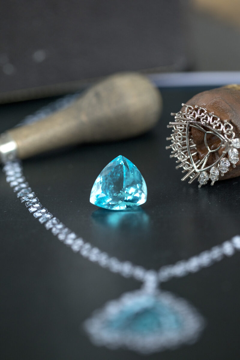 Blue gemstone beside an unfinished jewel setting and workshop tools in Chopard photography