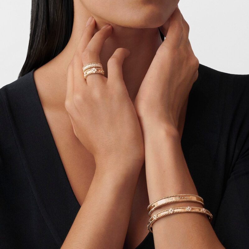 Van Cleef & Arpels gold bracelets and diamond-set ring worn with a black top