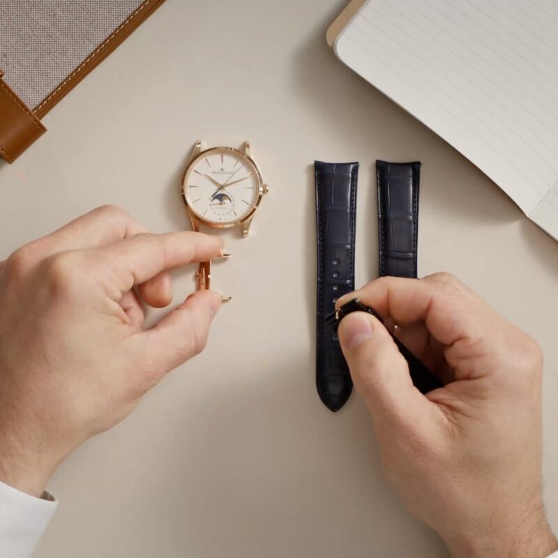 Hands comparing a Jaeger-LeCoultre watch with two spare leather straps