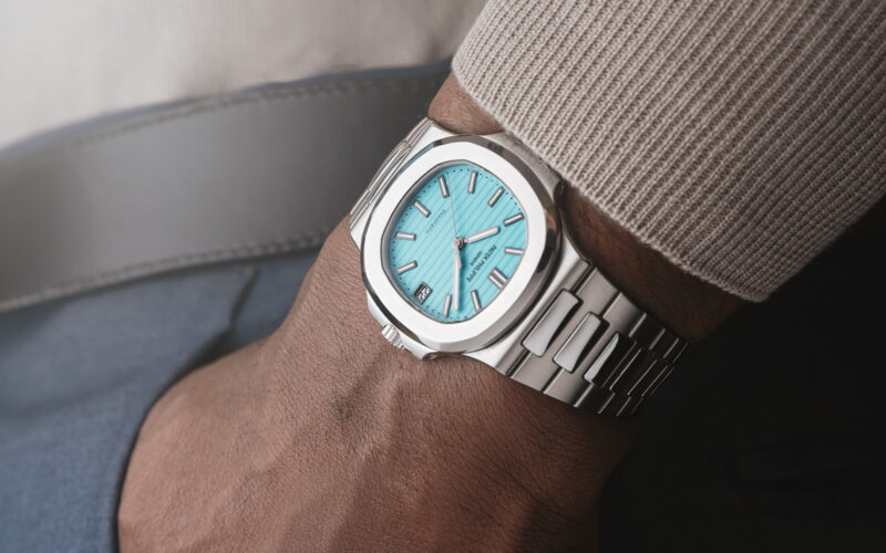 Turquoise-dial steel bracelet watch worn beneath a knitted cuff in Christie’s imagery