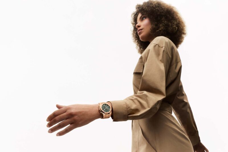 A woman wearing an Audemars Piguet watch in a light studio setting