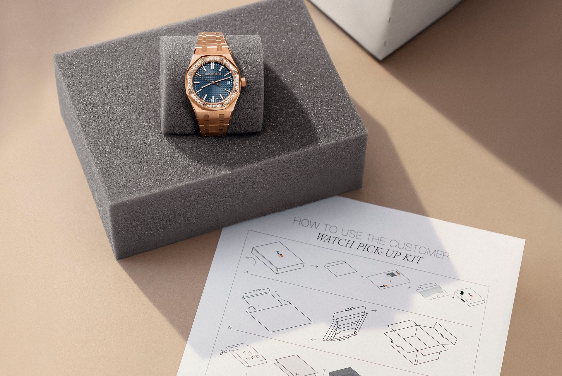 A Royal Oak watch beside a protective shipping cushion and service packaging instructions