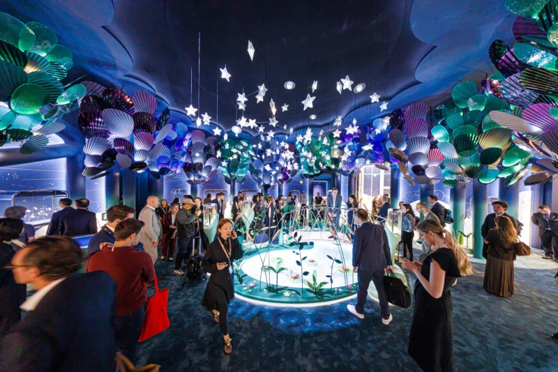 Visitors examining displays inside an illuminated Watches and Wonders Geneva 2026 booth