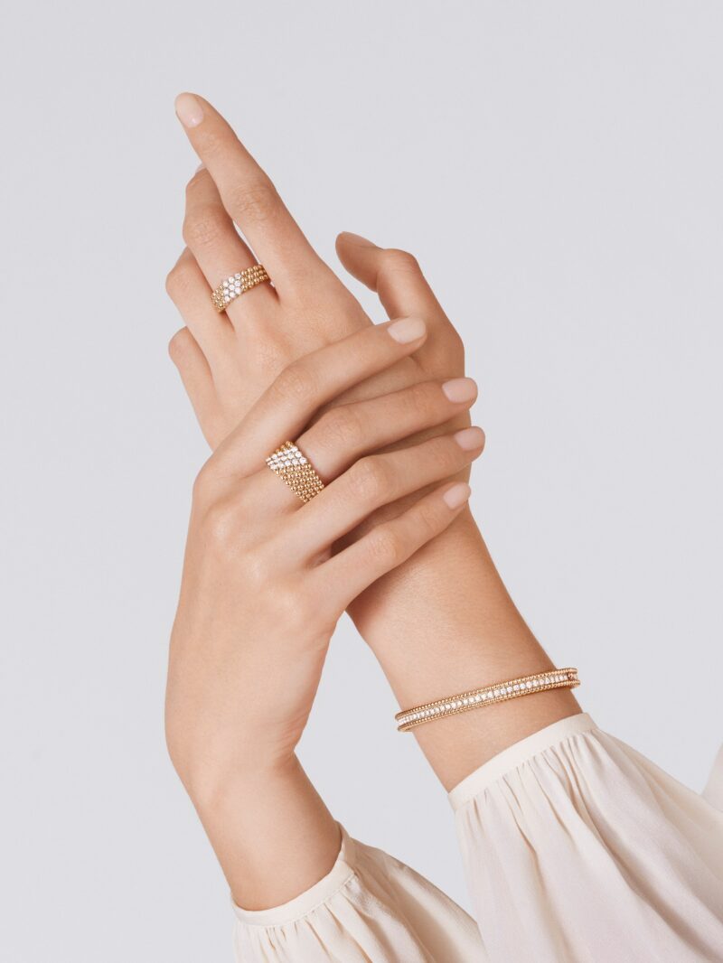 Close-up of a model hands wearing yellow gold Van Cleef & Arpels Perlee rings and a beaded Perlee bracelet
