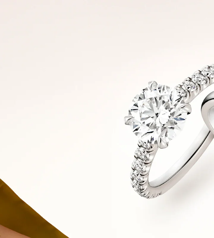 The Cartier Solitaire 1895 engagement ring resting on a white surface next to an open signature red Cartier ring box