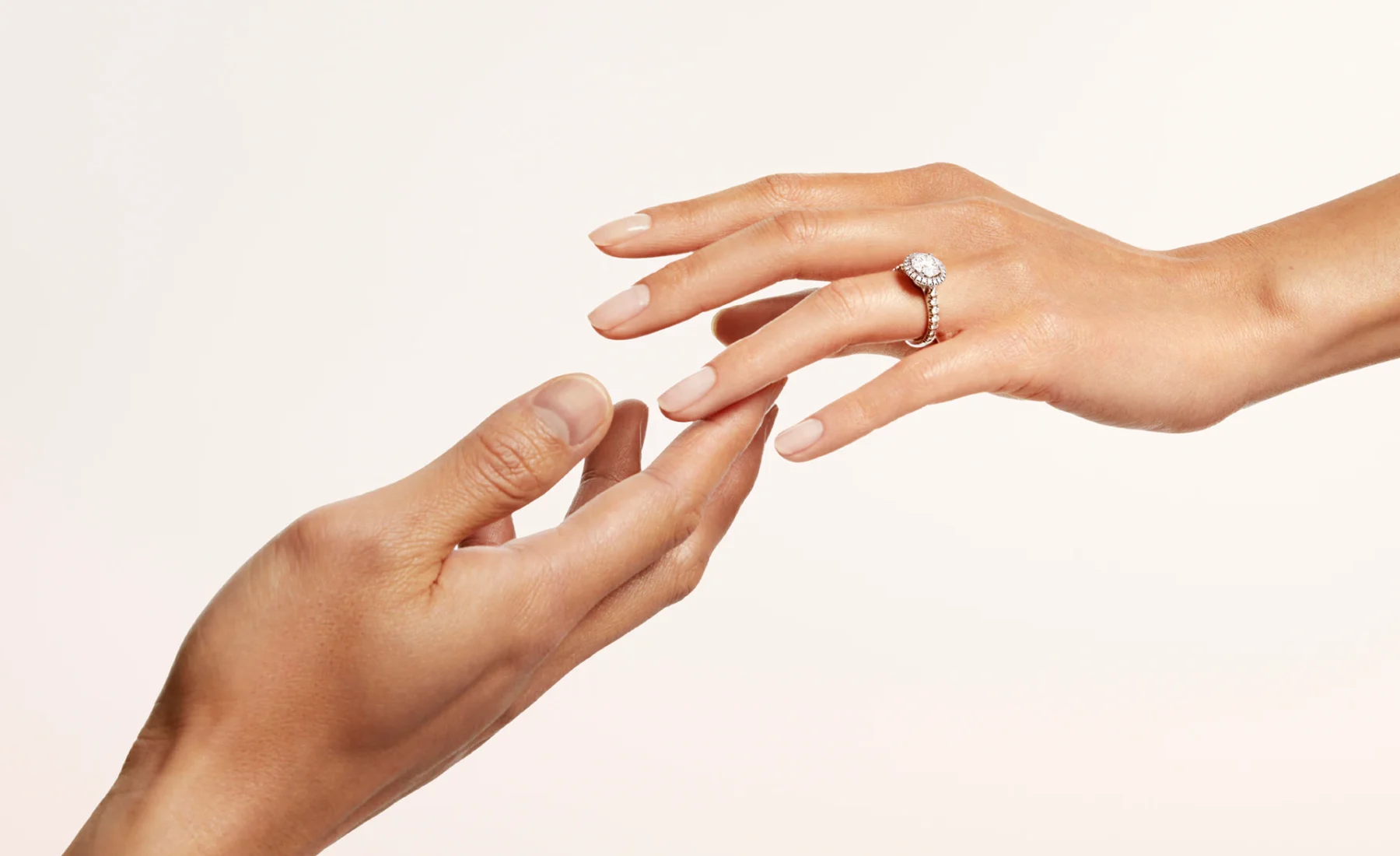 Close-up lifestyle shot of a couple clasping hands, with the woman wearing a plain Cartier Trinity ring