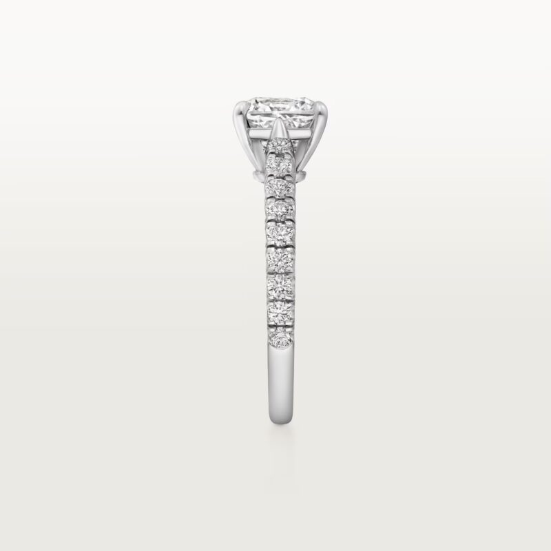 Angled studio shot of the plain Cartier Trinity ring casting shadows on a white surface