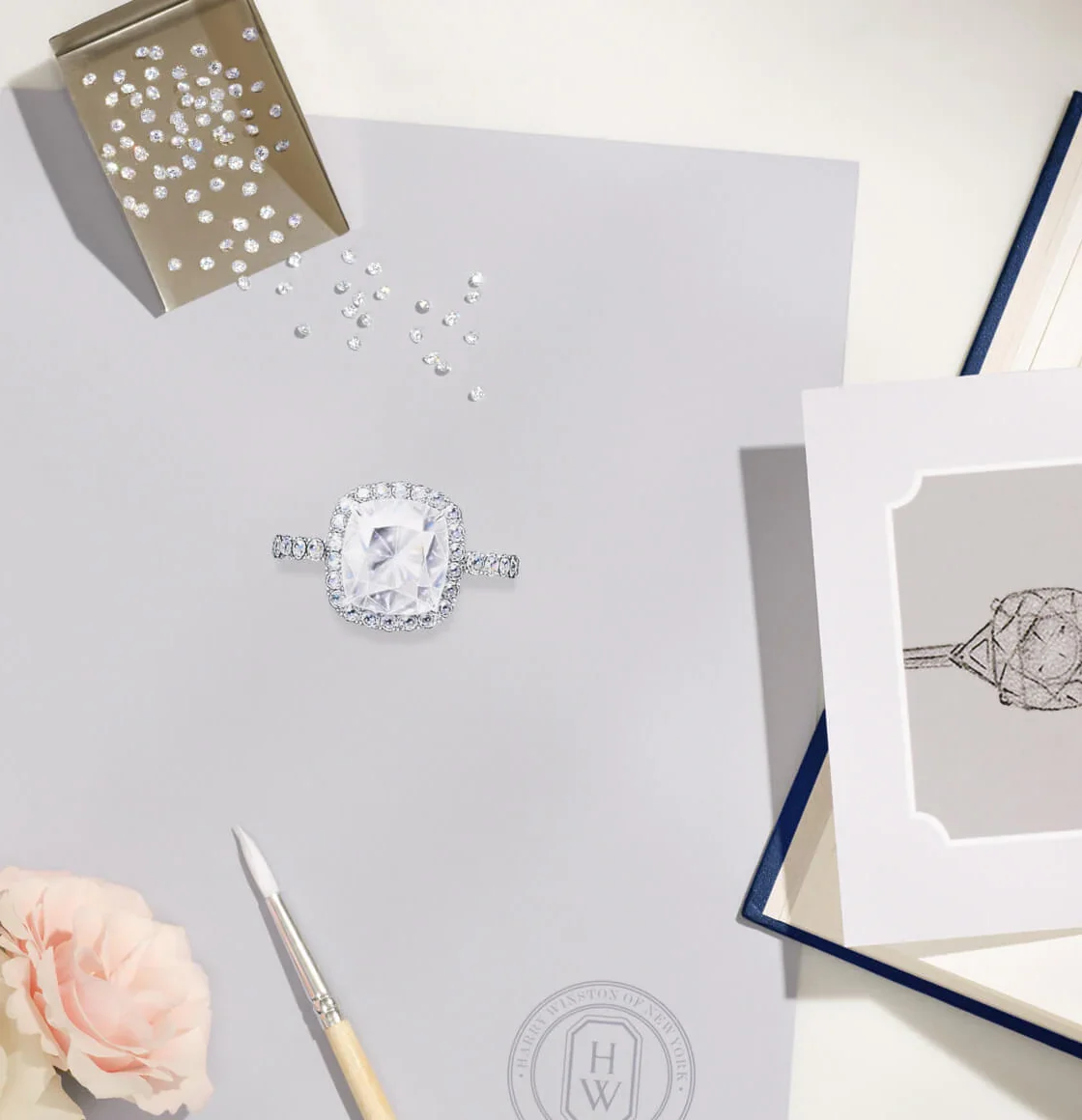 Flat lay of two Harry Winston engagement rings next to official GIA grading report certificates and blue leather envelopes
