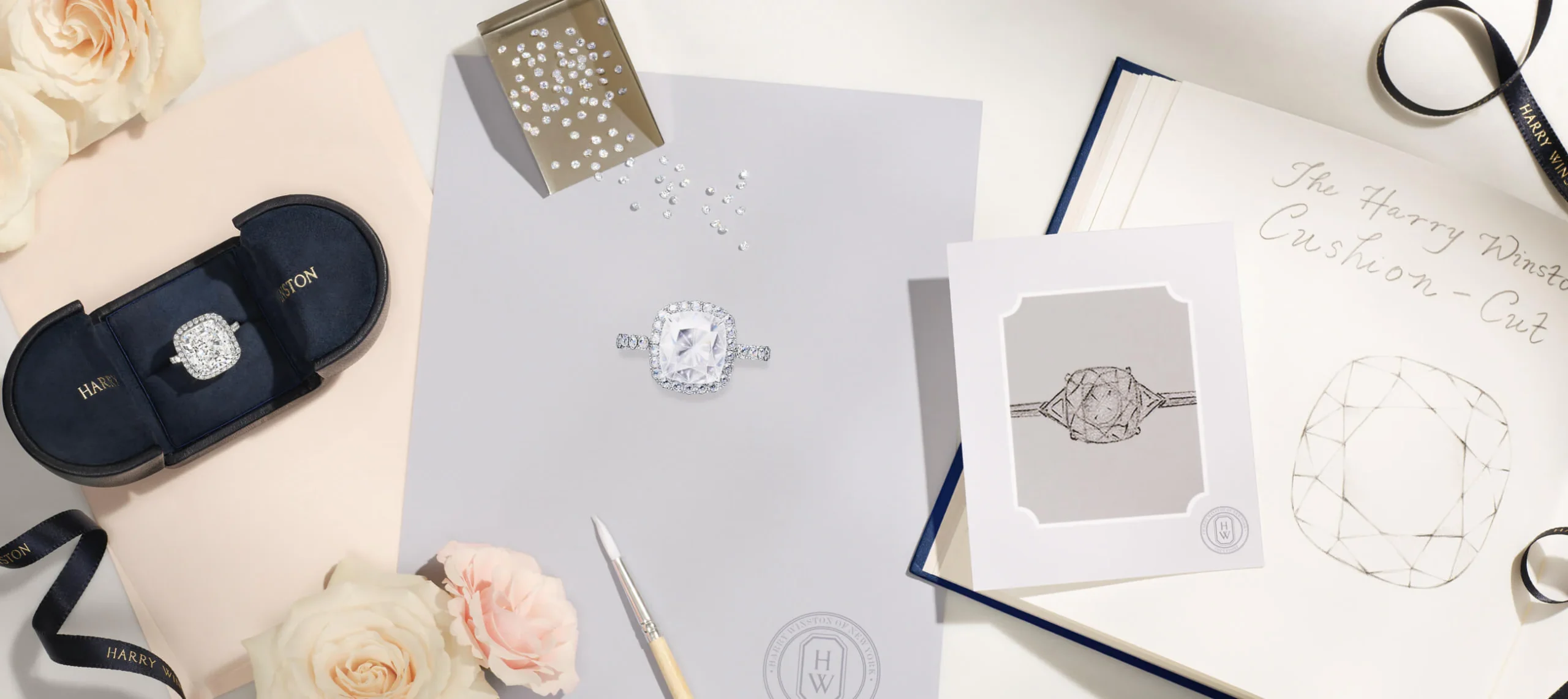 Flat lay of two Harry Winston engagement rings next to official GIA grading report certificates and blue leather envelopes