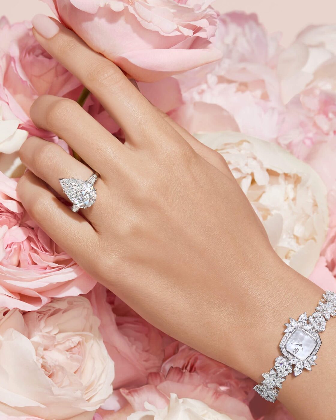 Close-up of a model hand wearing a Harry Winston pear-shaped solitaire engagement ring against a soft background
