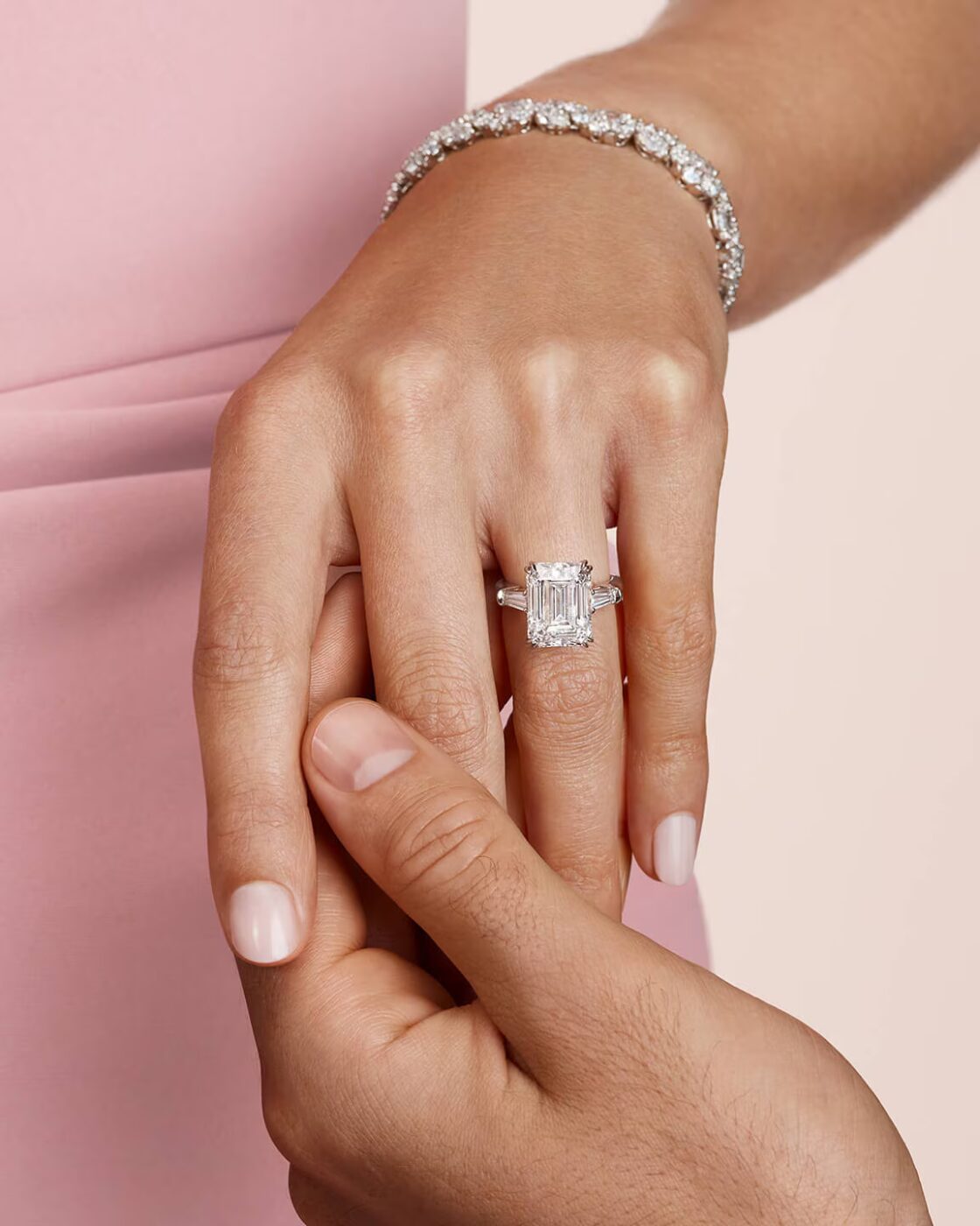 Model wearing an emerald-cut Harry Winston solitaire engagement ring and a micropave band on her finger