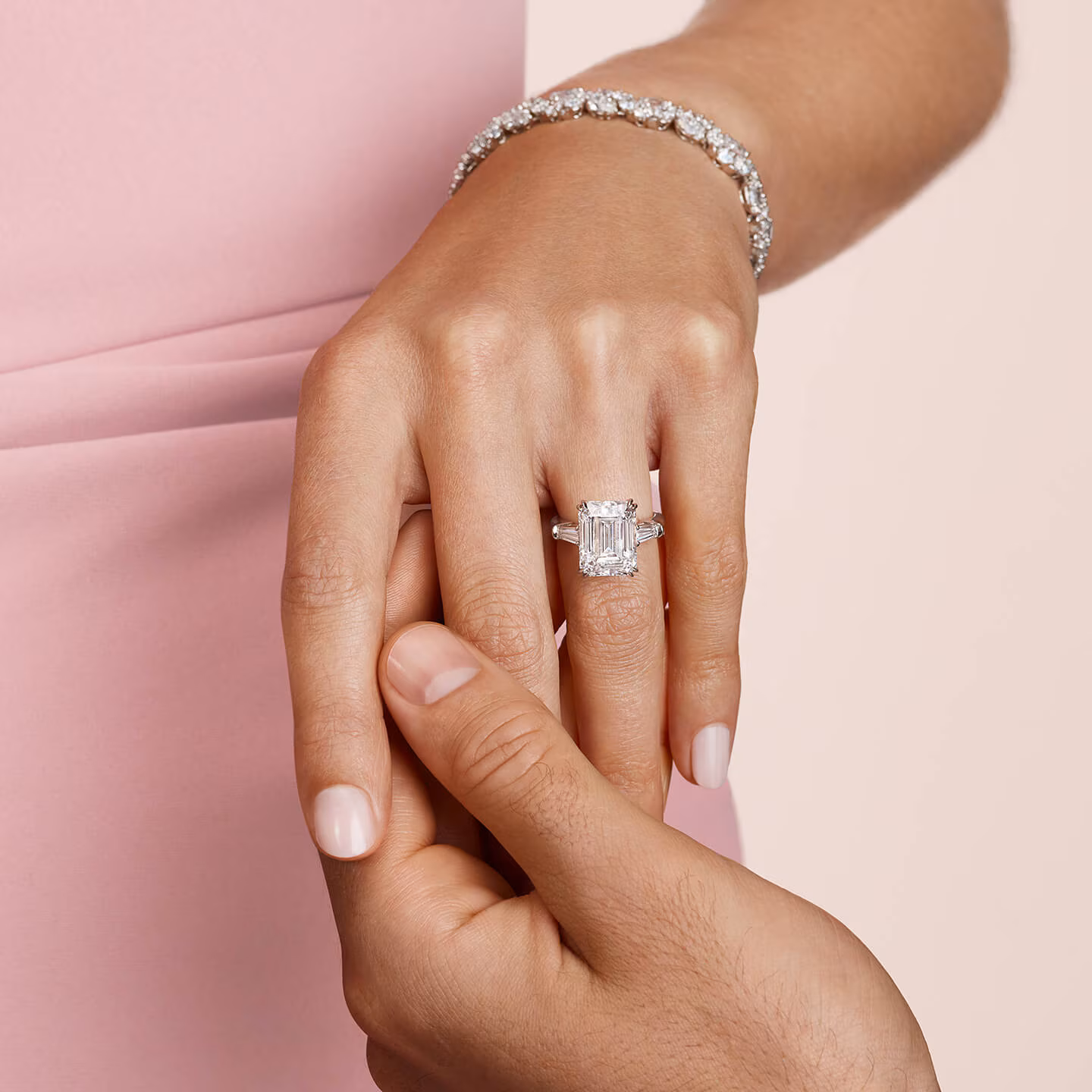Model wearing an emerald-cut Harry Winston solitaire engagement ring and a micropave band on her finger