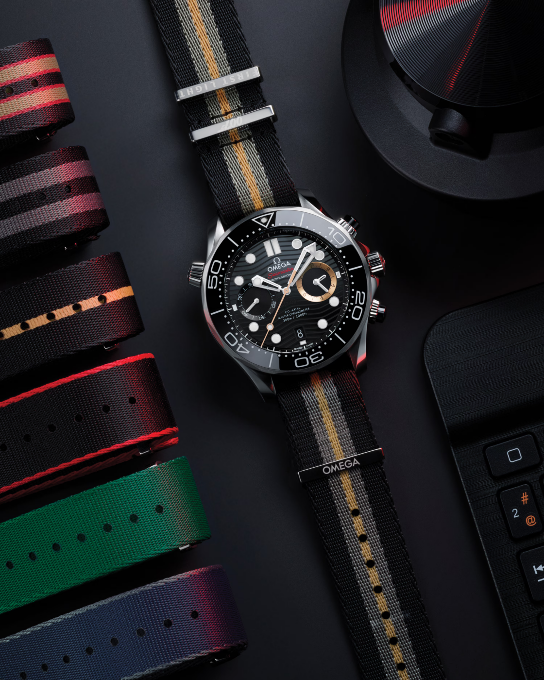 Flat-lay of the Omega Seamaster Diver 300M Chronograph 007 First Light watch next to various alternative striped NATO straps