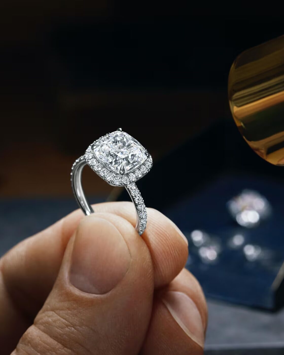 A master craftsman at the Harry Winston atelier using a loupe and precision tools to mount diamonds onto a platinum setting