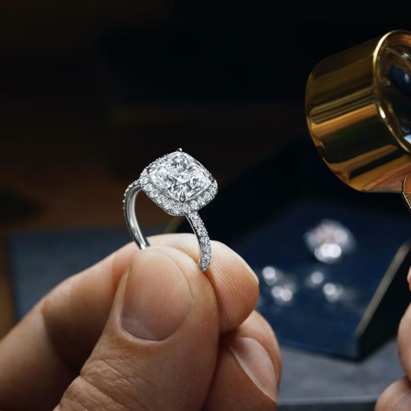 A master craftsman at the Harry Winston atelier using a loupe and precision tools to mount diamonds onto a platinum setting