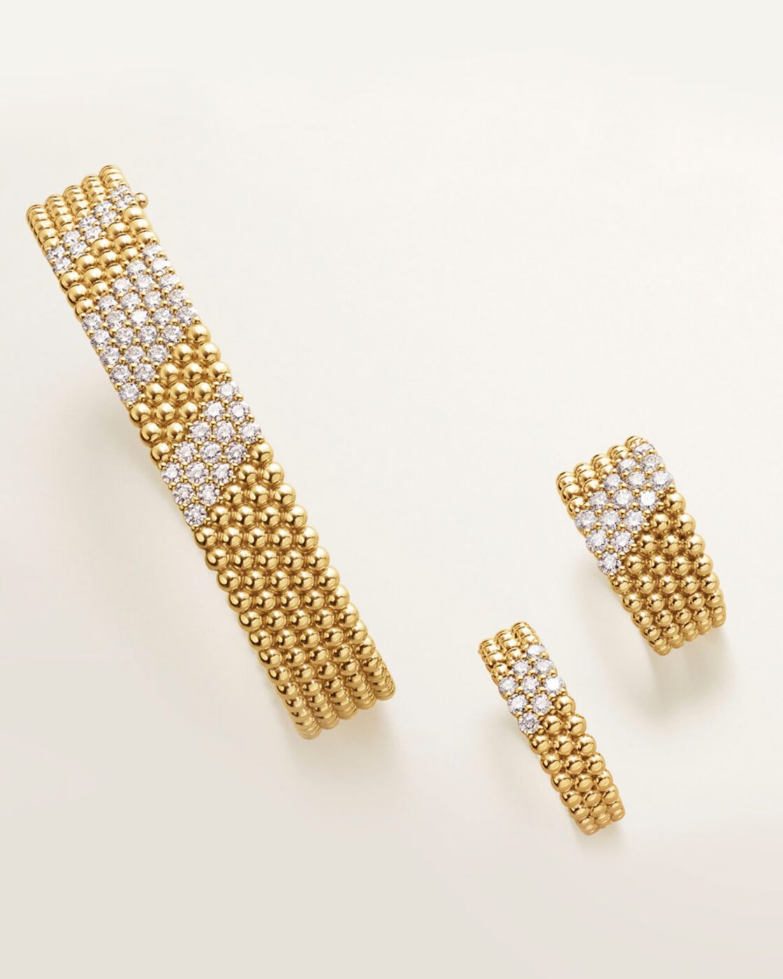 Flat-lay photo of a wide yellow gold Perlée bracelet paved with diamonds and two matching Perlée diamond rings