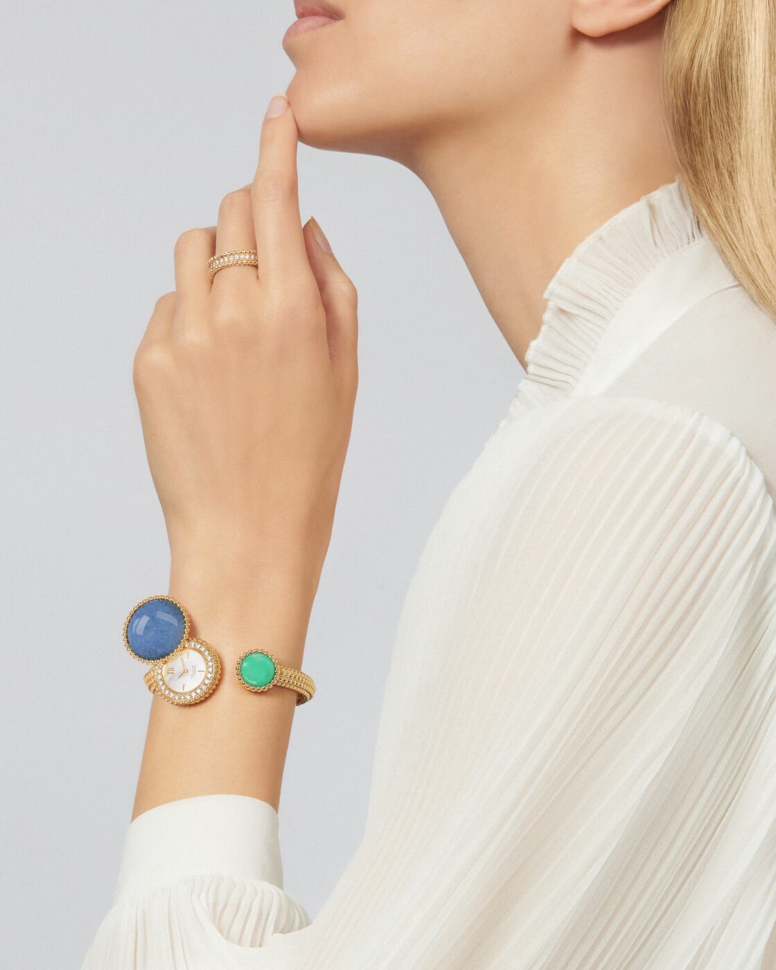 Blonde model in profile wearing a white high-neck top, Perlée ring, and Perlée Toi & Moi secret watch on her wrist