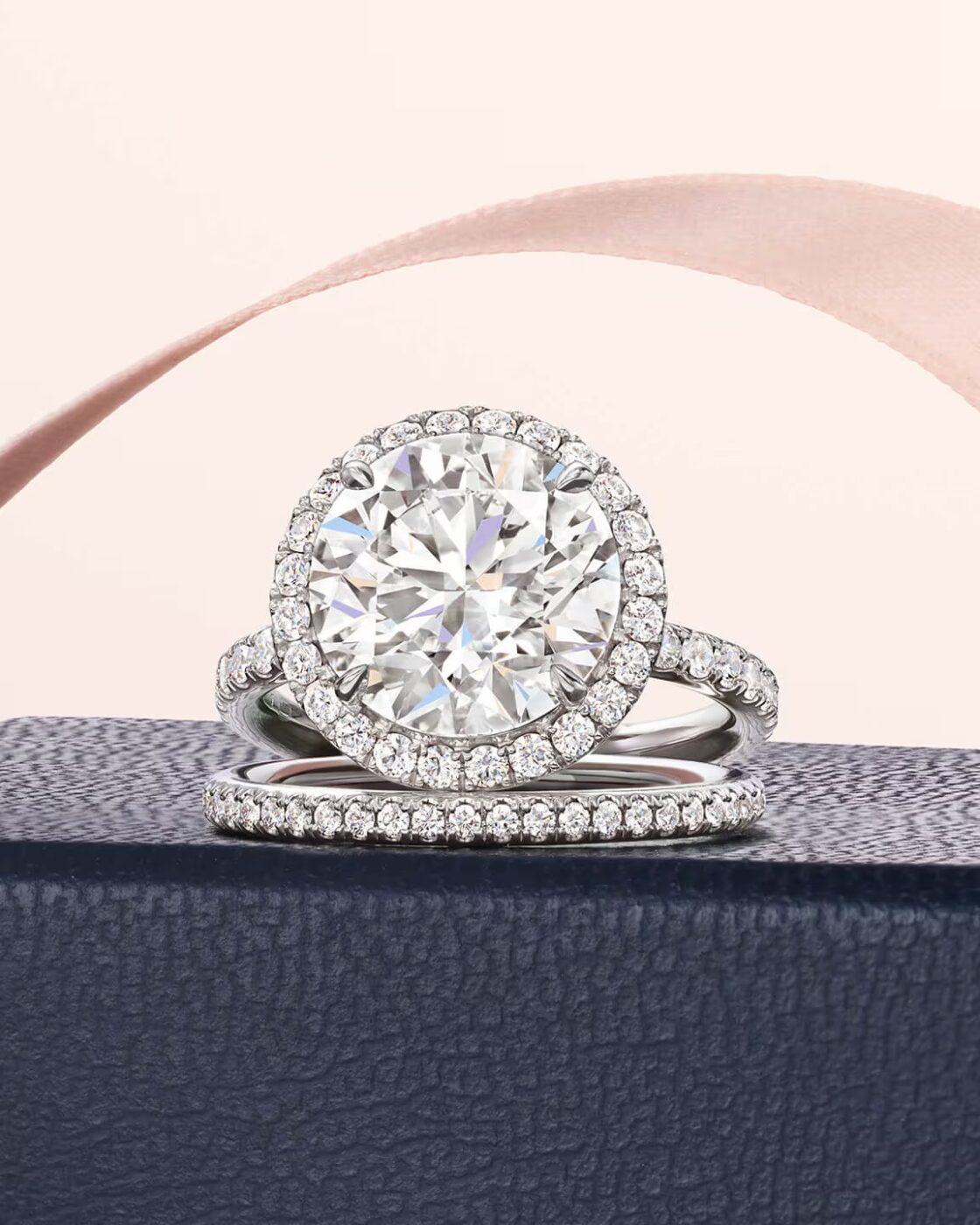 A Classic Winston round brilliant cut solitaire diamond ring resting on a white silk ribbon