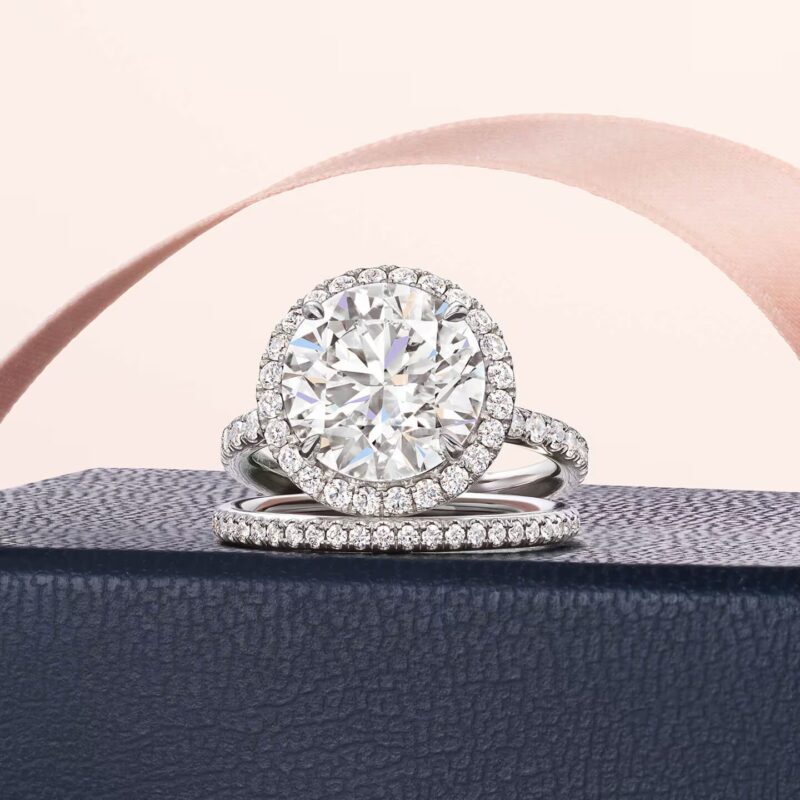 A Classic Winston round brilliant cut solitaire diamond ring resting on a white silk ribbon