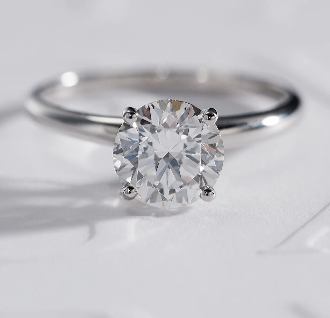 A classic Bulgari solitaire engagement ring sitting on a white background with debossed Bulgari brand name text