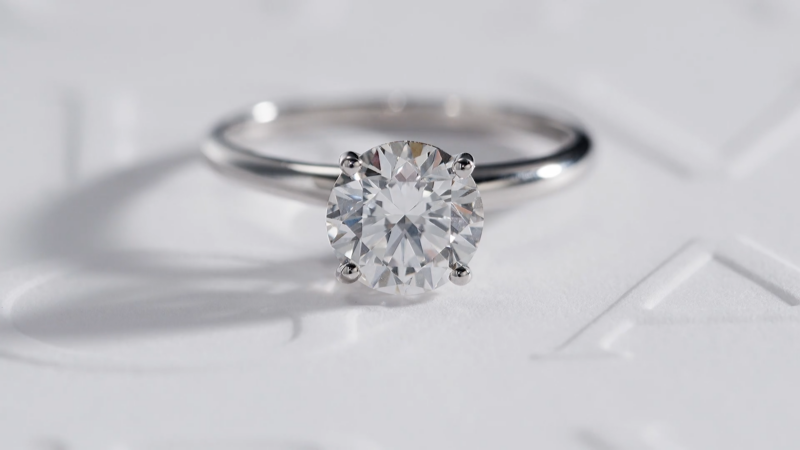 A classic Bulgari solitaire engagement ring sitting on a white background with debossed Bulgari brand name text