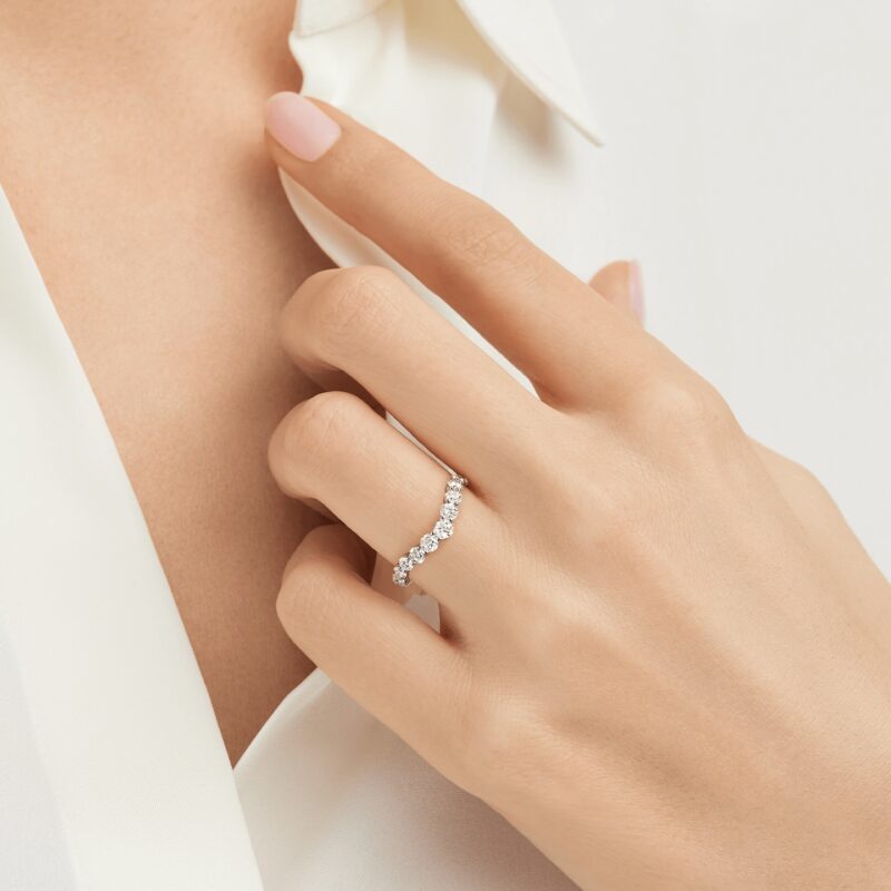 Hand wearing the Harry Winston Winston Truly diamond band against white clothing.