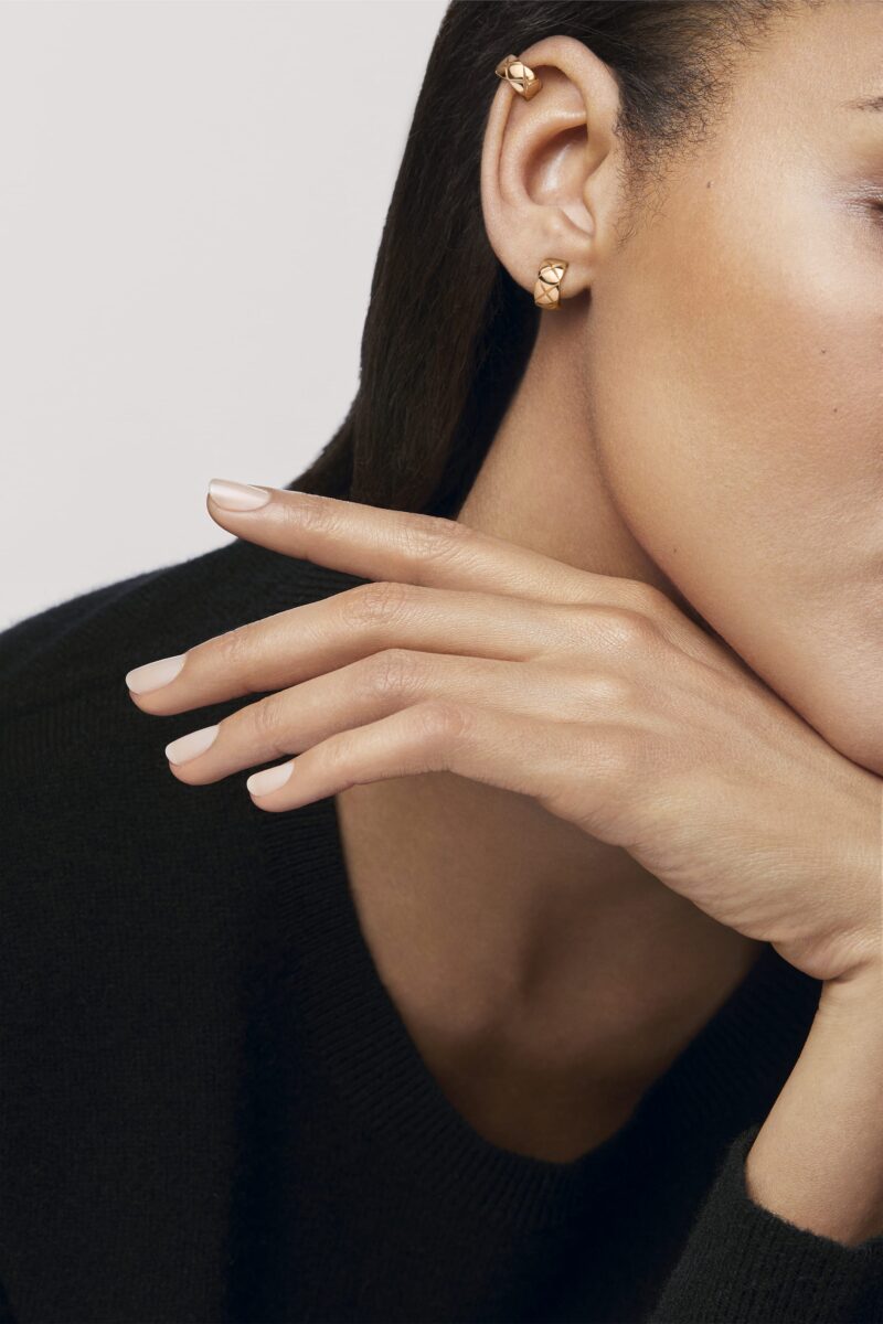 Close view of an ear wearing two CHANEL COCO CRUSH BEIGE GOLD earrings at the lobe and upper ear.