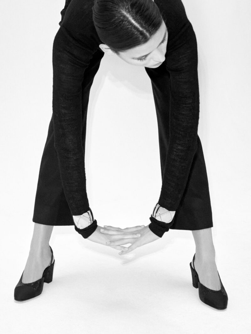 Black-and-white portrait showing CHANEL COCO CRUSH cuffs worn one on each wrist.