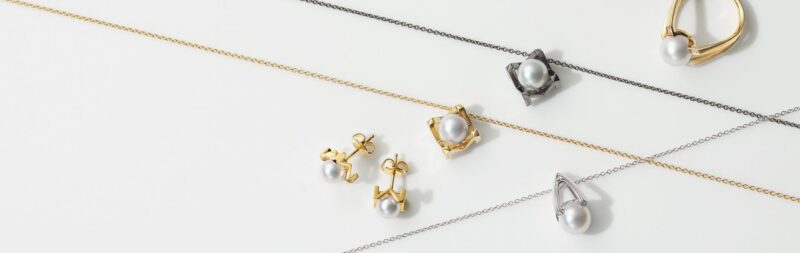 Panoramic Mikimoto M Collection jewellery arrangement with graphic gold settings and pearls.