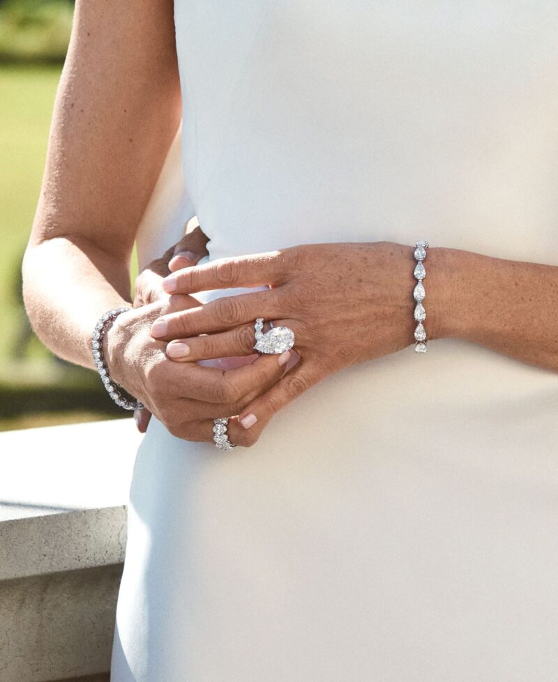 Pear-shaped diamond solitaire worn against white bridal fabric.