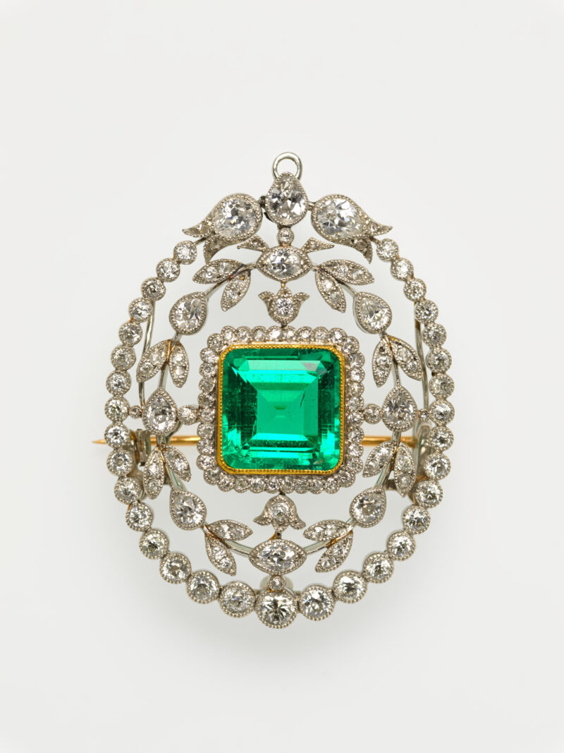 An emerald brooch framed by diamonds in platinum, front view.