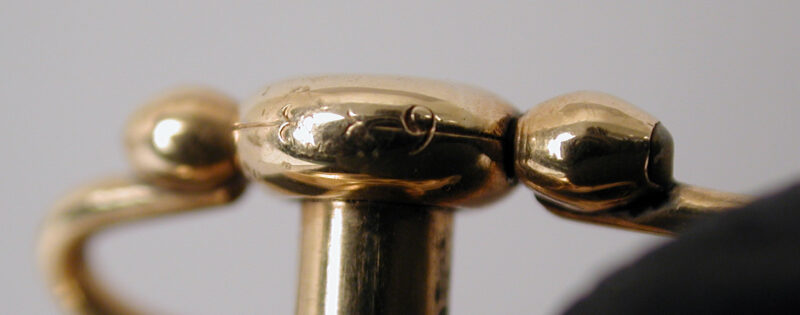 Gold pendant and ring of the skeleton watch, seen from the side.