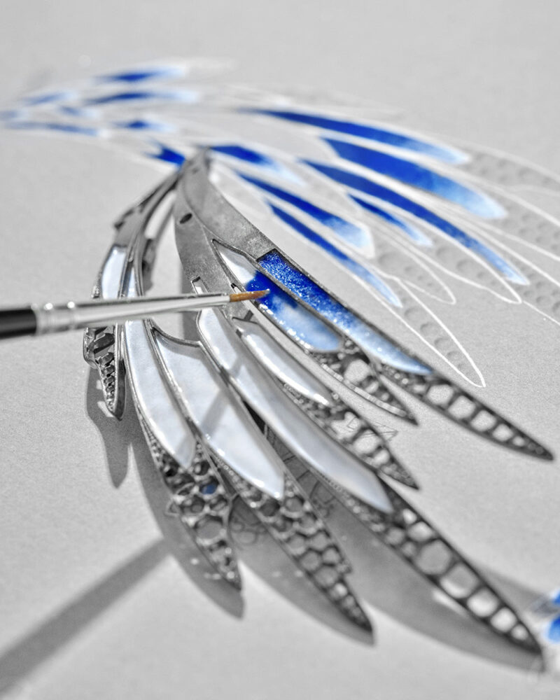 Tool touching the underside of layered blue wings above an open lattice support.