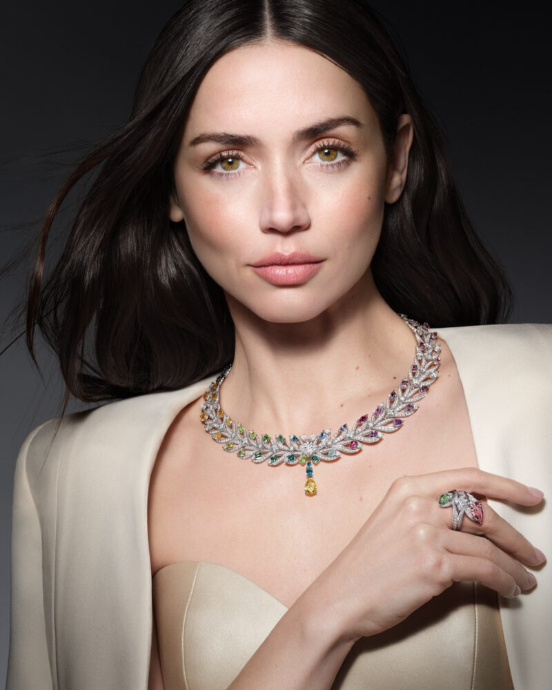 Ana de Armas wearing the multicoloured Victory necklace with a yellow drop and a ring beside her shoulder.