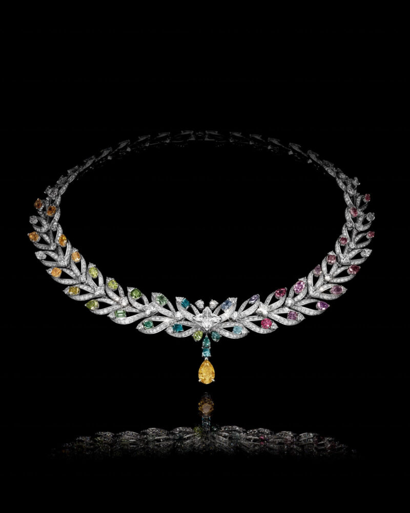 Victory necklace on black, coloured accents moving around a bright curved outline with a yellow drop at the front.